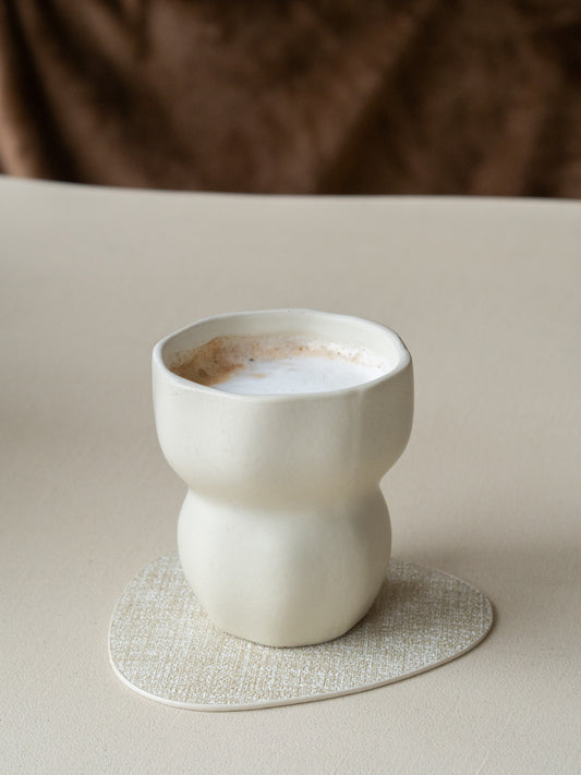 organische onderzetter van beige leer op houten tafel met koffiekopje