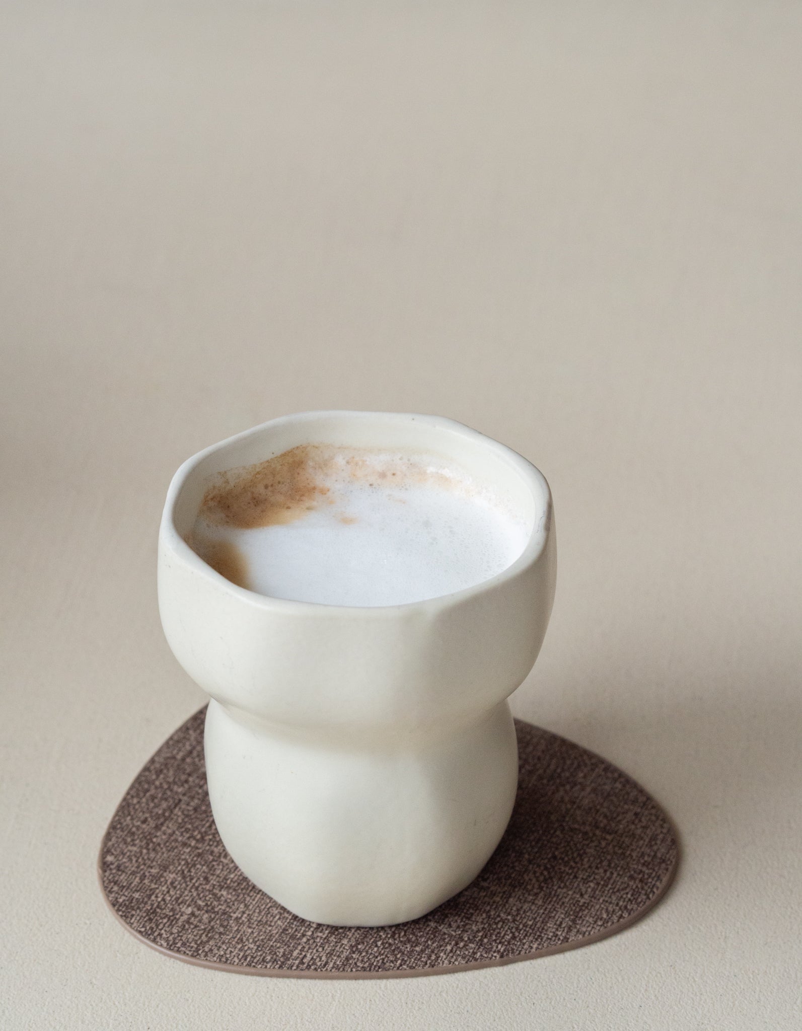 Organische onderzetter van bruin leer op houten tafel met koffiekopje